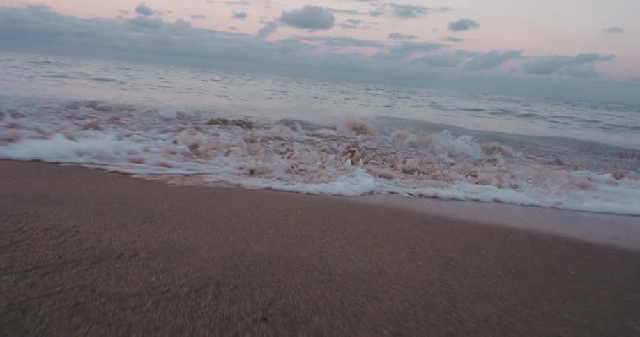 Wave breaking and foamy water reaching the beach sand