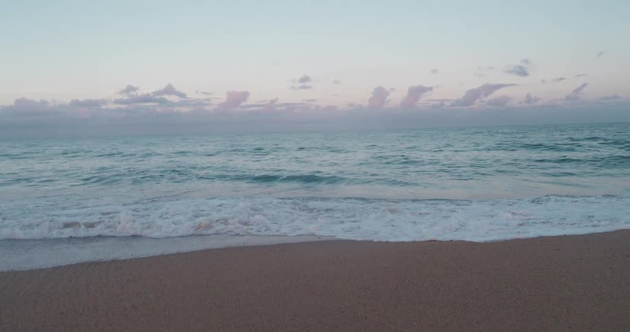 A twilight beach scene with waves crashing onto the shore