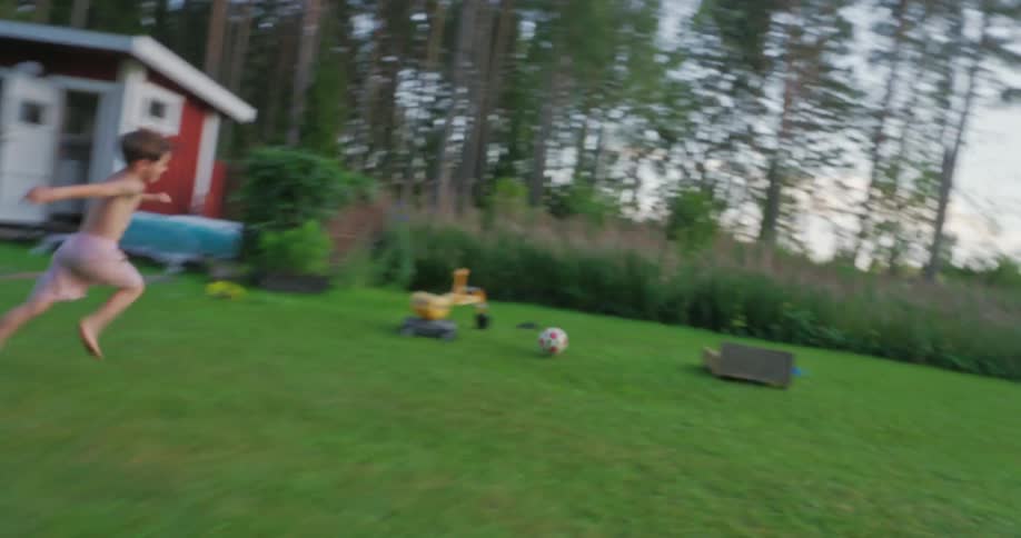 Grandfather kicks a soccer ball and his young grandson chases after it
