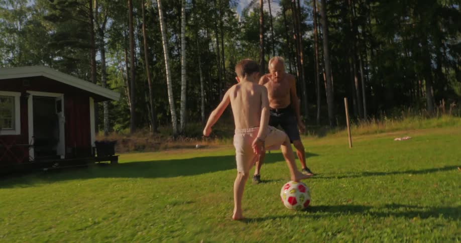 Father and son kick a soccer ball back and forth in their backyard