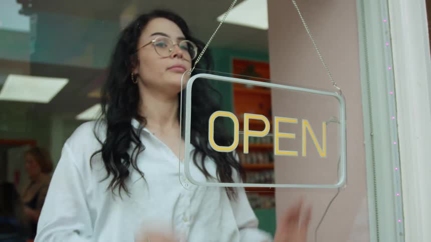 Woman turning off a light sign in a store that said open