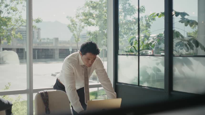 Man in a tie in an office room in front of a laptop