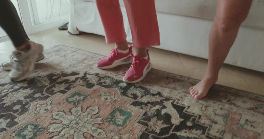 An elderly woman and two other women are dancing in the living room