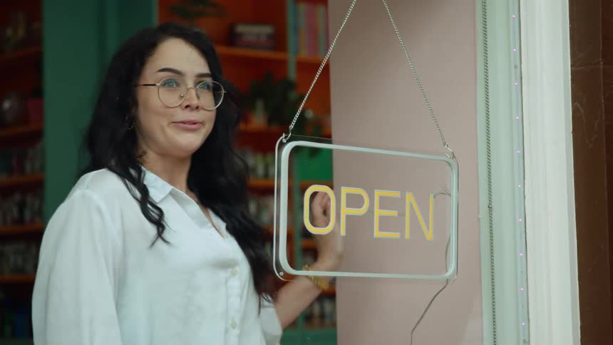 Woman turning off a neon sign in the window of a store