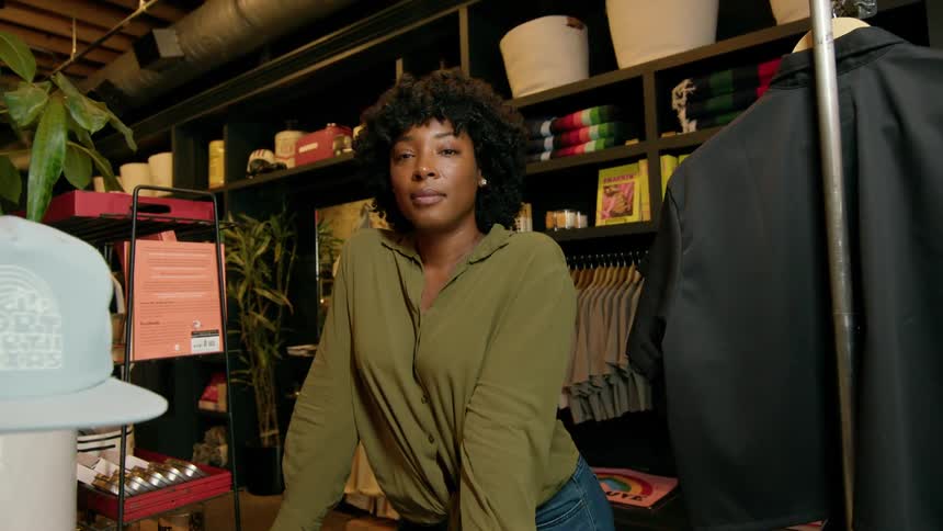 Woman poses in a clothes shop next to a clothes rack