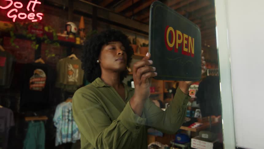 Woman turns a closed sign to open at a souvenir shop