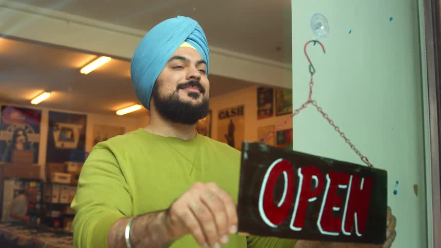 A man turns around a sign to signify his gift shop is open