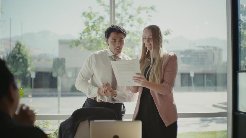 Man stands to join the conversation held by coworkers during an office meeting