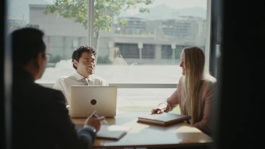 Man and woman sitting at an office desk with a laptop and talking