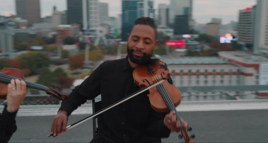 Man and two women on the terrace of a building playing the violin