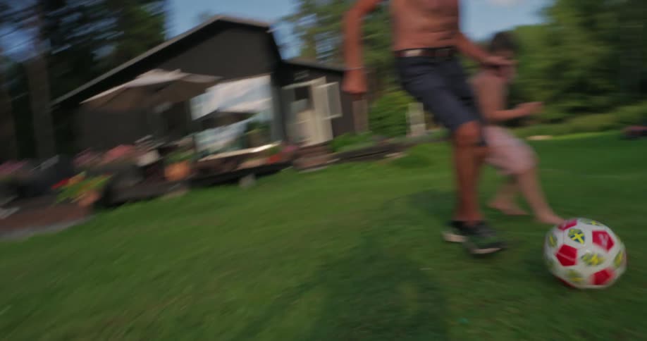 Grandfather playing ball in the grassy backyard with his grandson