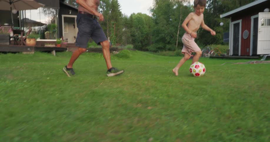 A grandfather and grandson play soccer together