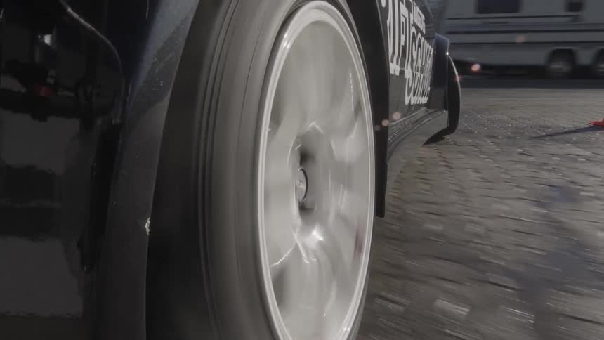 A closeup of a cars wheel in motion with the tire spinning on asphalt
