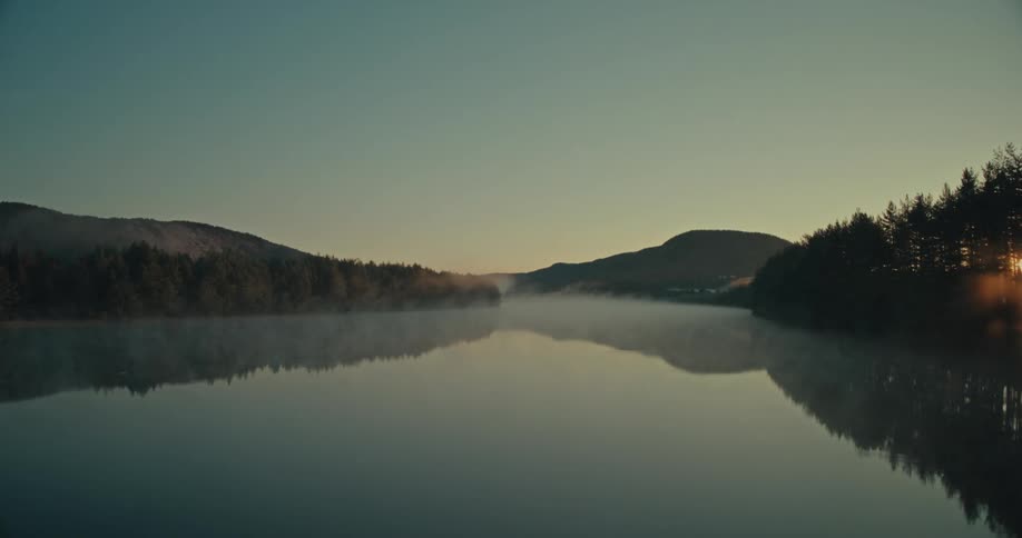 Sunrise landscape with a serene lake and mountains and forests around