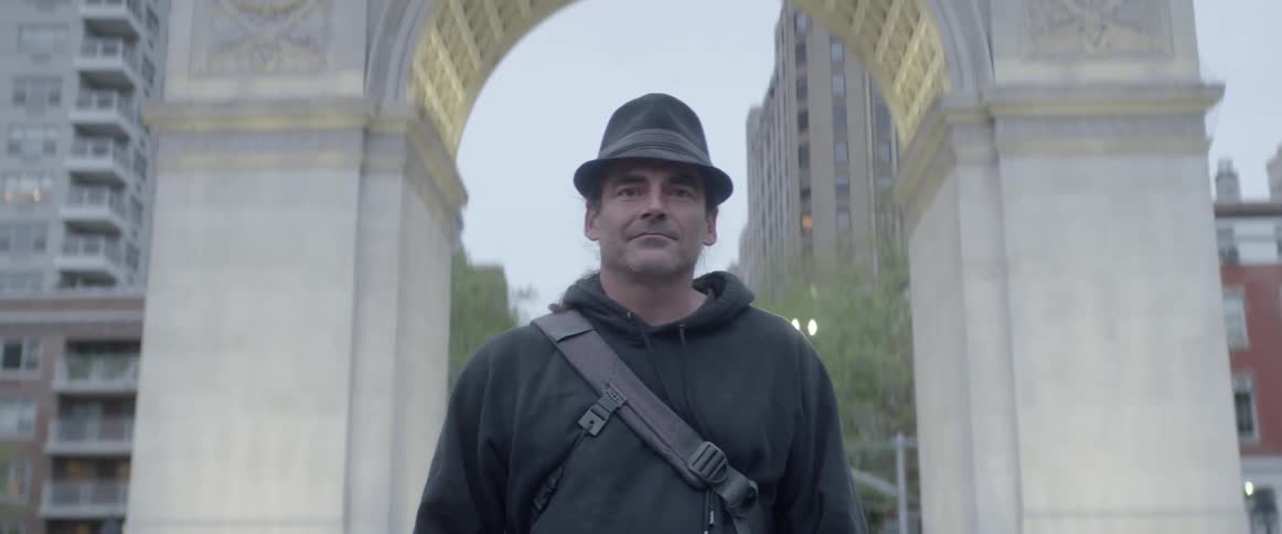 Tourist standing in a city with an archway just behind him