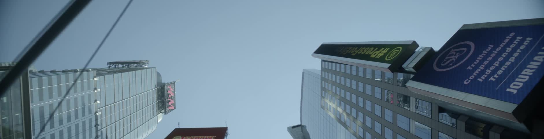 View looking up at tall buildings with passing street lights in a city