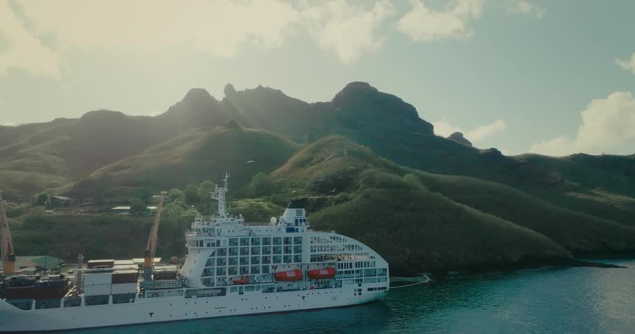 Aerial view of a ship with containers in a port on the edge of mountains