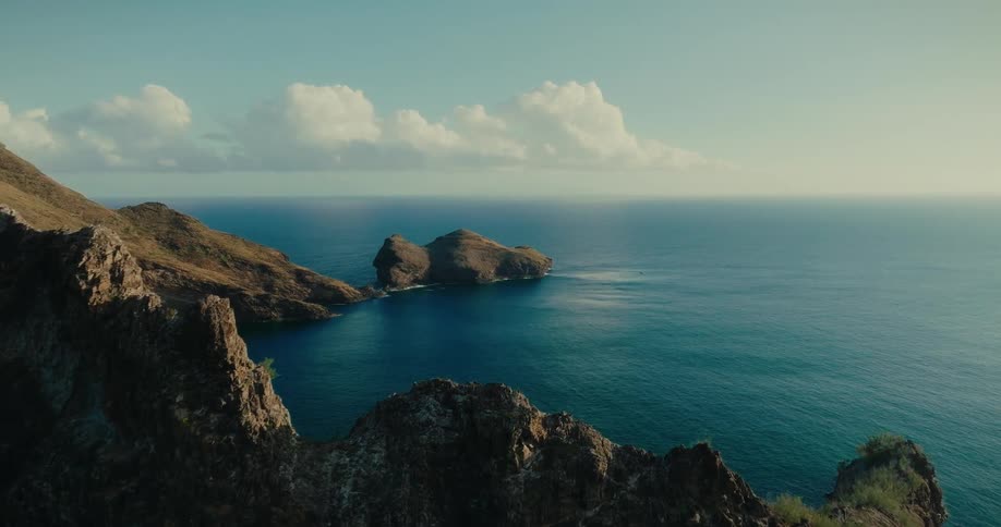 Aerial landscape of rocky coastline by the sea on a blue sky day