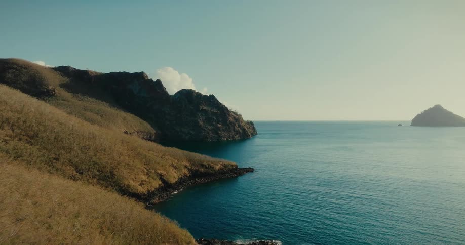 Natural scenery with a rocky and greenish bet by the sea on a clear sky day