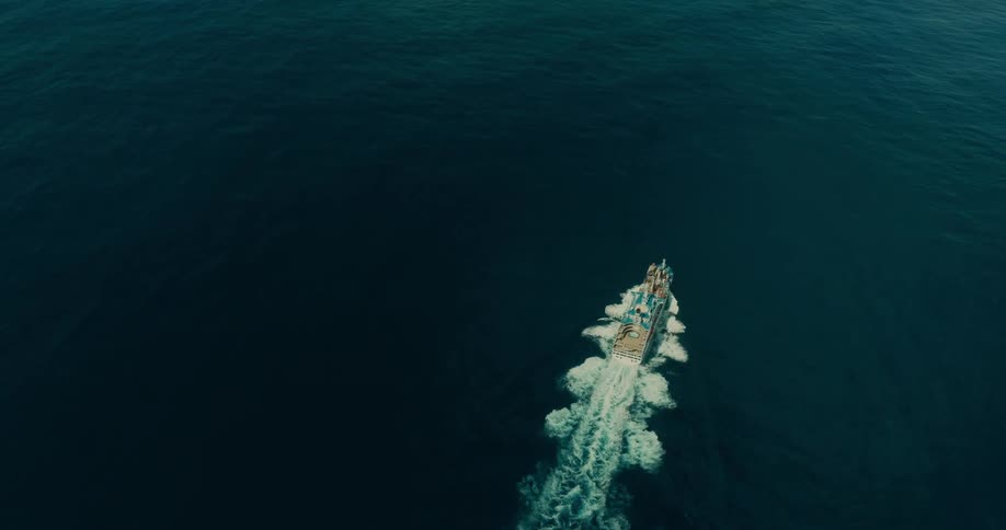 Top view of a ship sailing across an ocean and leaving trails