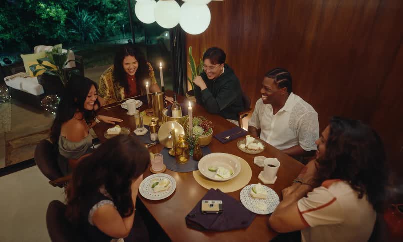 Group of friends sitting at a table laughing and chatting at a table full of dishes and drinks