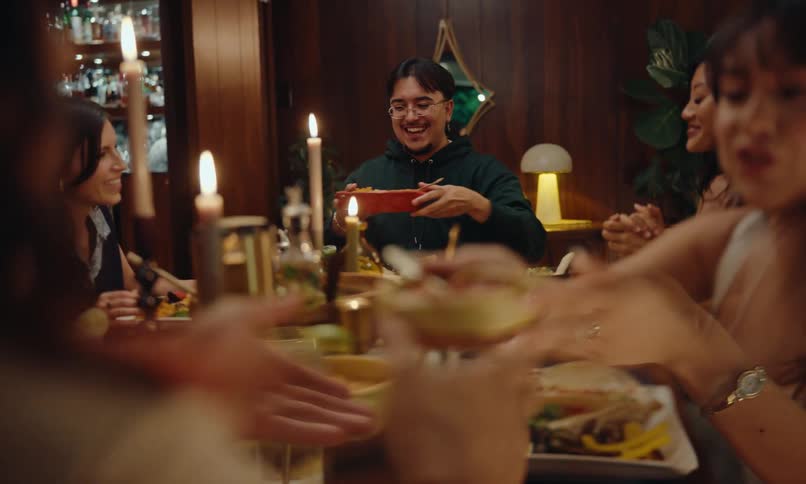 Group of friends sitting at the table sharing dishes and serving themselves