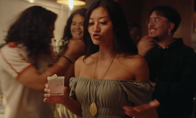 Group of friends in the kitchen with drinks in hand and chatting at a party