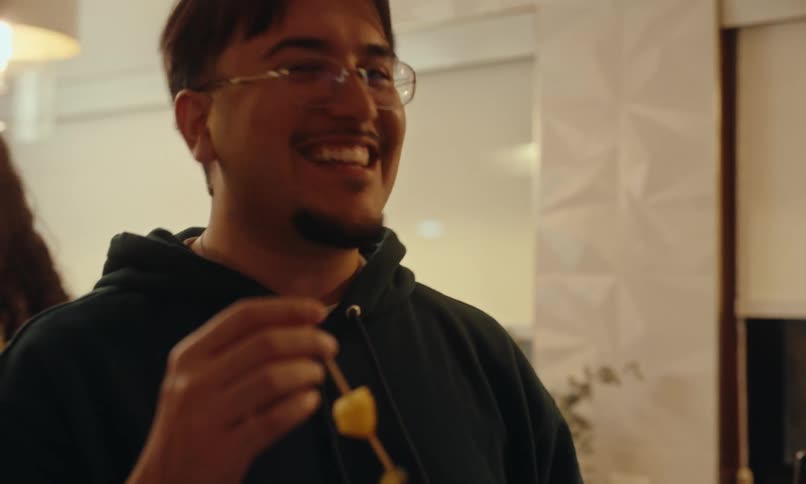 Portrait of a man holding a fruit skewer talking to some friends at a party