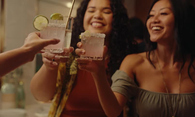 A group of three women toasting their drinks and they are happy