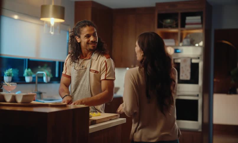 Woman hugs man cooking in their kitchen at night
