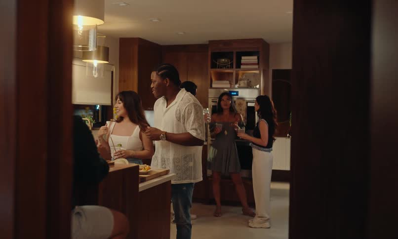 Friends in a kitchen with drinks in hand chatting at a party