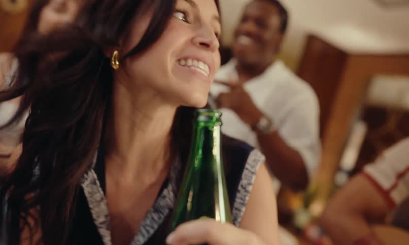 Portrait of a woman holding a beer and dancing with a group of friends around her