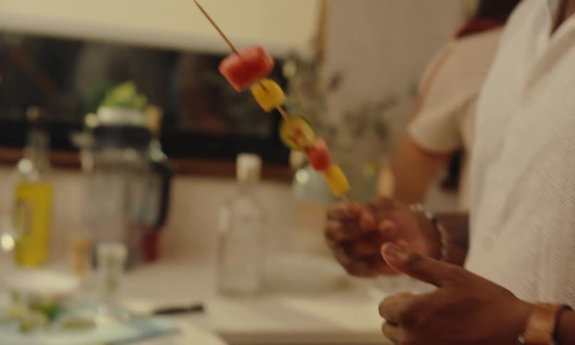 A couple of friends handling skewers with grilled vegetables