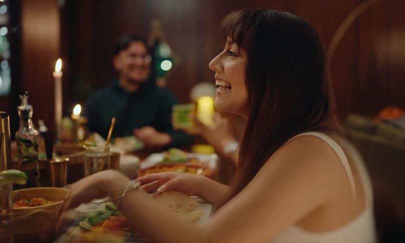 Portrait of a woman sitting at a table talking to other people around her