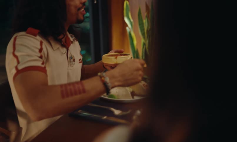 Several people are around a table full of plates and bowls of food and they are serving the food