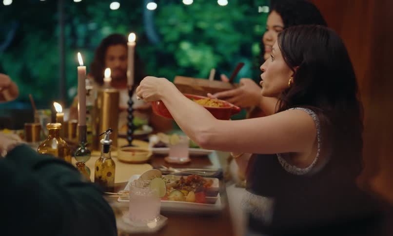 Friends gathered at a dinner table serving themselves and chatting at a celebration