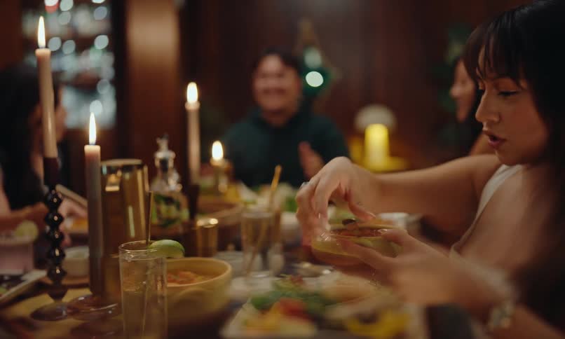 A cheerful group of friends talking while gathered around a large dinner table filled with plenty of food