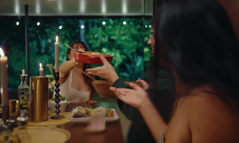 Friends sitting at the dinner table serving themselves and chatting