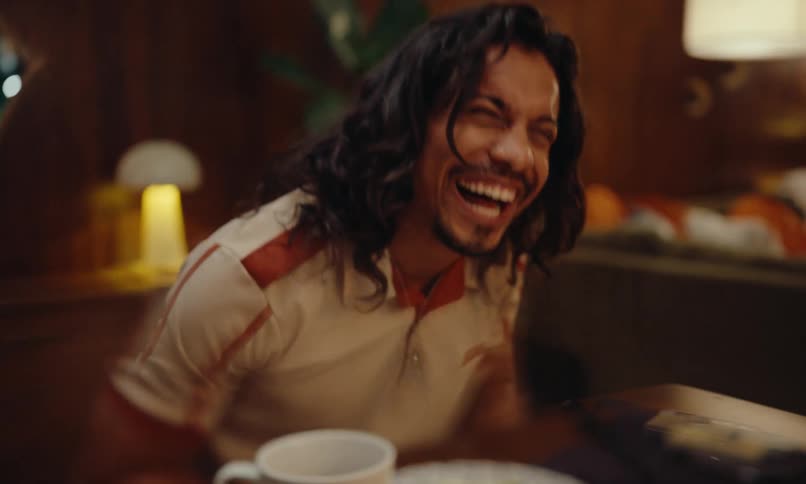 Portrait of a man sitting at a dinner table at night laughing out loud