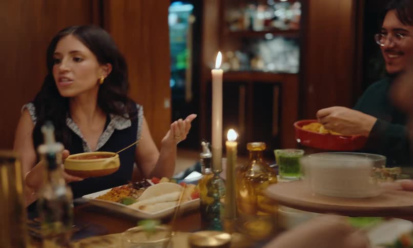 Group of friends at a celebration sitting at a table serving themselves plates of food