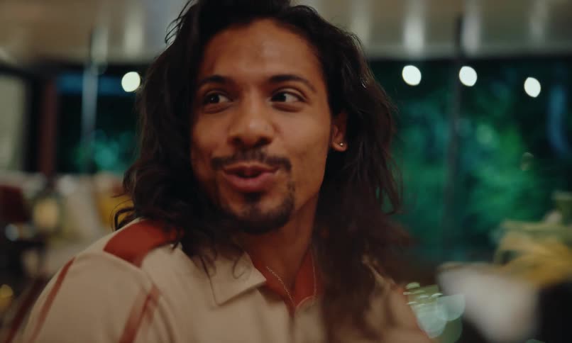 A man laughs while conversing with friends over dinner at a restaurant