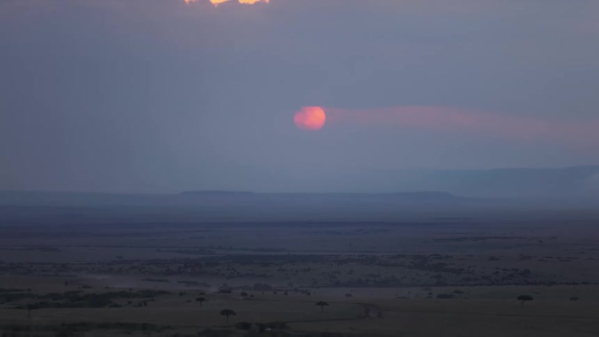 Panorama of a green field leading to the reddish moon on the horizon