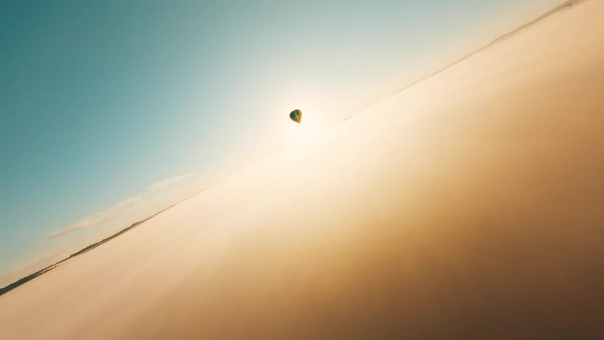 Aerial panorama of a sea of clouds with a colorful balloon on a sunset horizon
