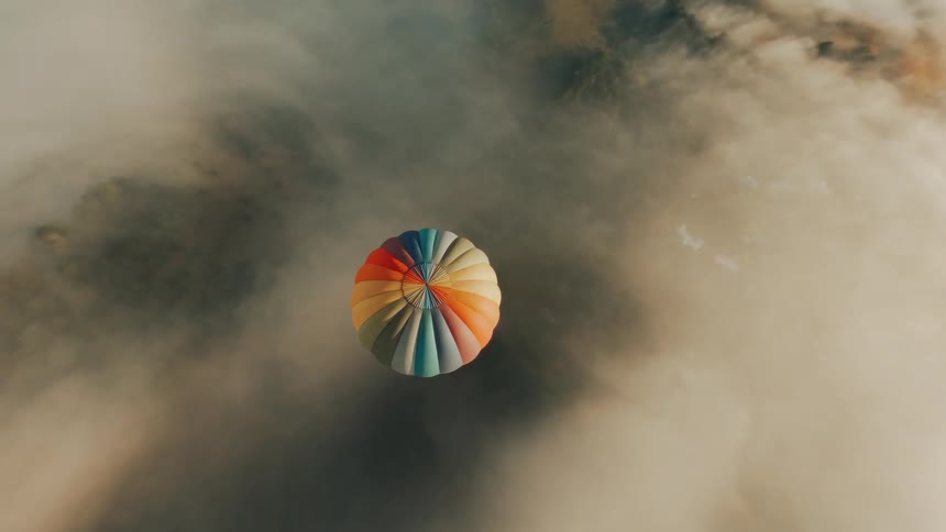 A colorful hot air balloon floats in the sky above the haze