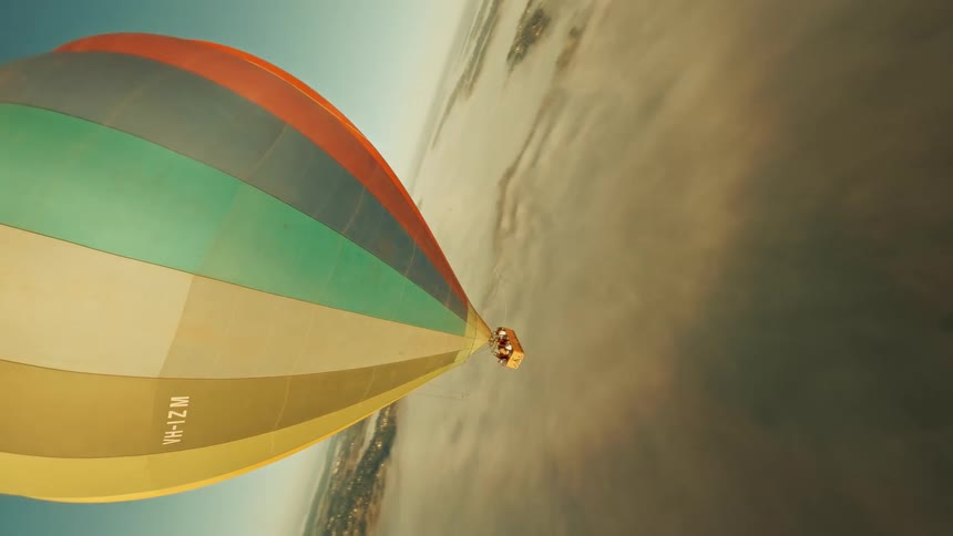An aerial view of a colorful air balloon floating above the landscape