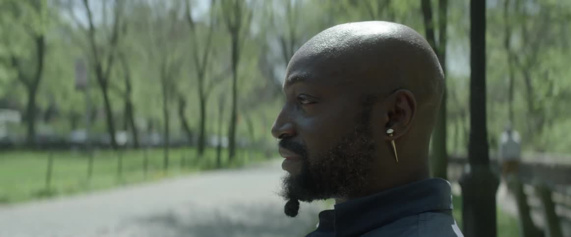 Man with a spiked earring sitting on a park bench