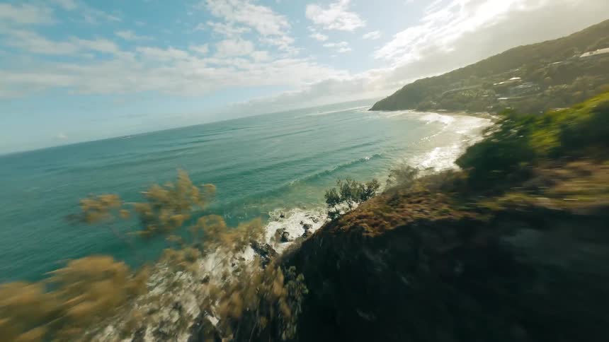Aerial view of a car driving on a coastal road in the mountains next to the ocean