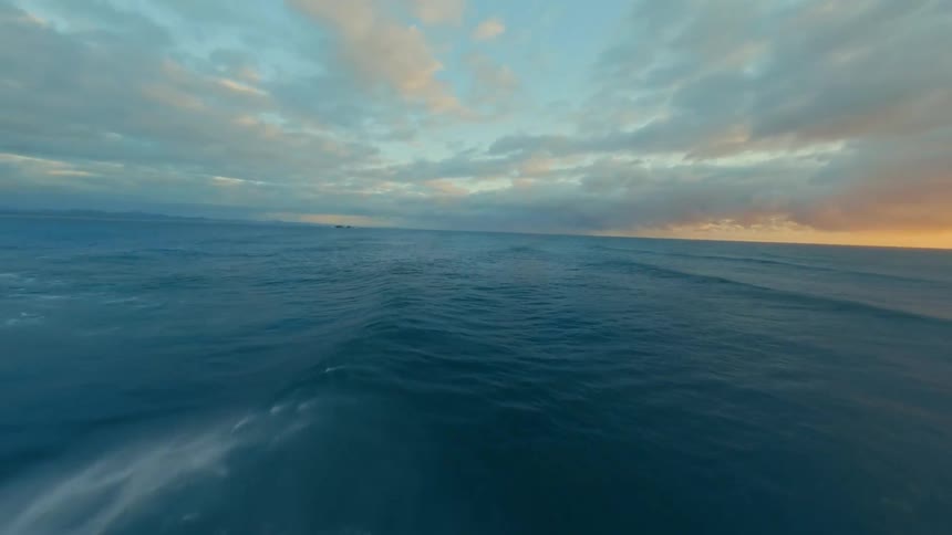 Aerial landscape of a vast sea with waves and the orange sky on the horizon