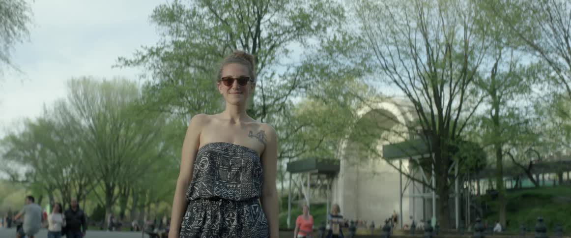 A woman is standing in a park and smiling on a sunny day