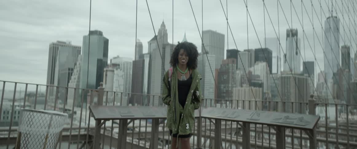 A woman is smiling posing in front of a city behind her